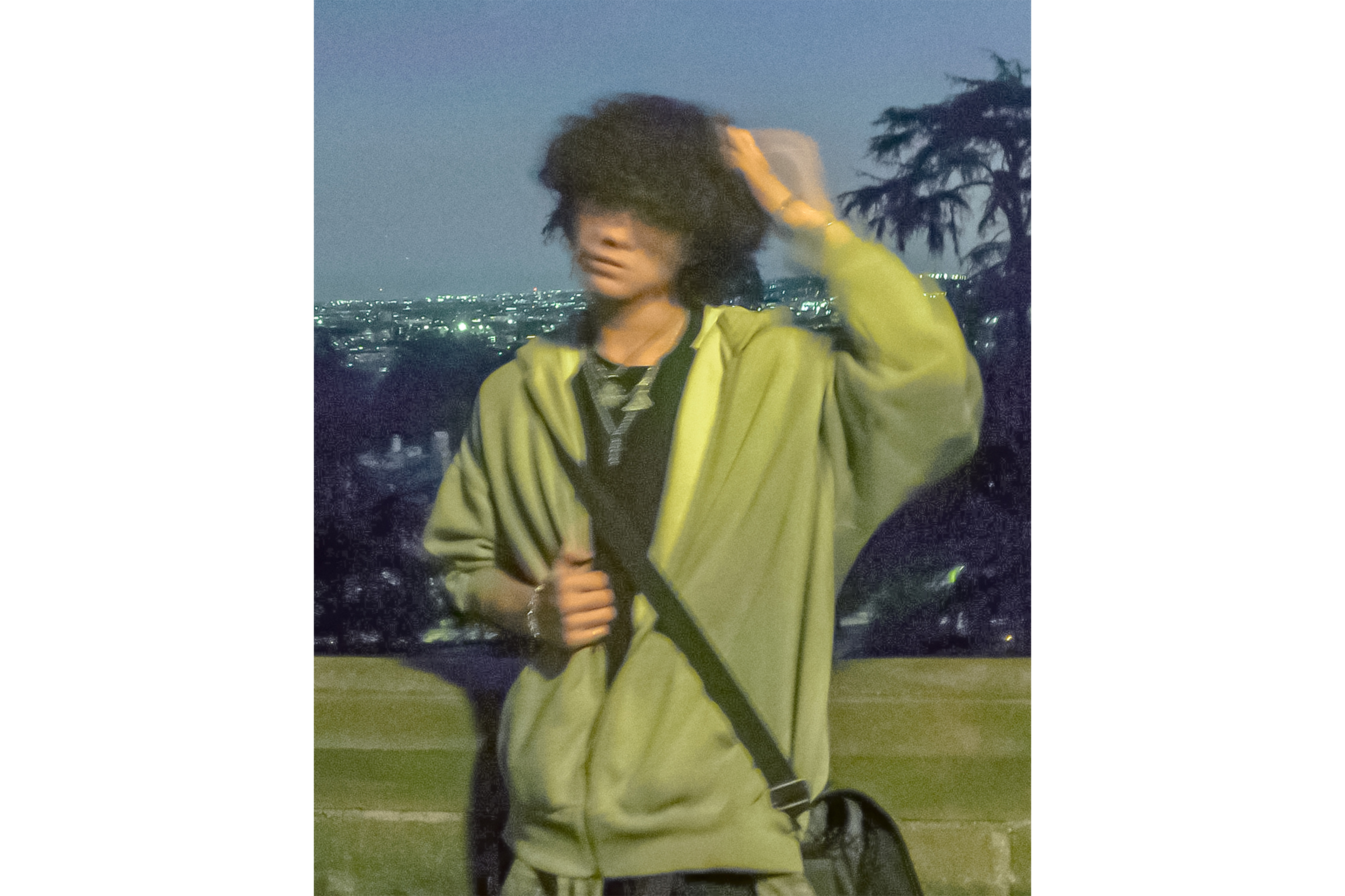 Dea stands in front of the camera at dusk with the skyline of the city behind him, wearing a gray hoodie. The artist said his six-track EP creates a cohesive storyline that ties each song together.  (Courtesy of Dea/Altered from original)