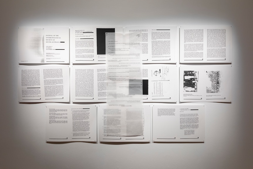 (un)silenced by Jayda Wilson featuring black and white printed sheets of paper arranged on a gallery wall.