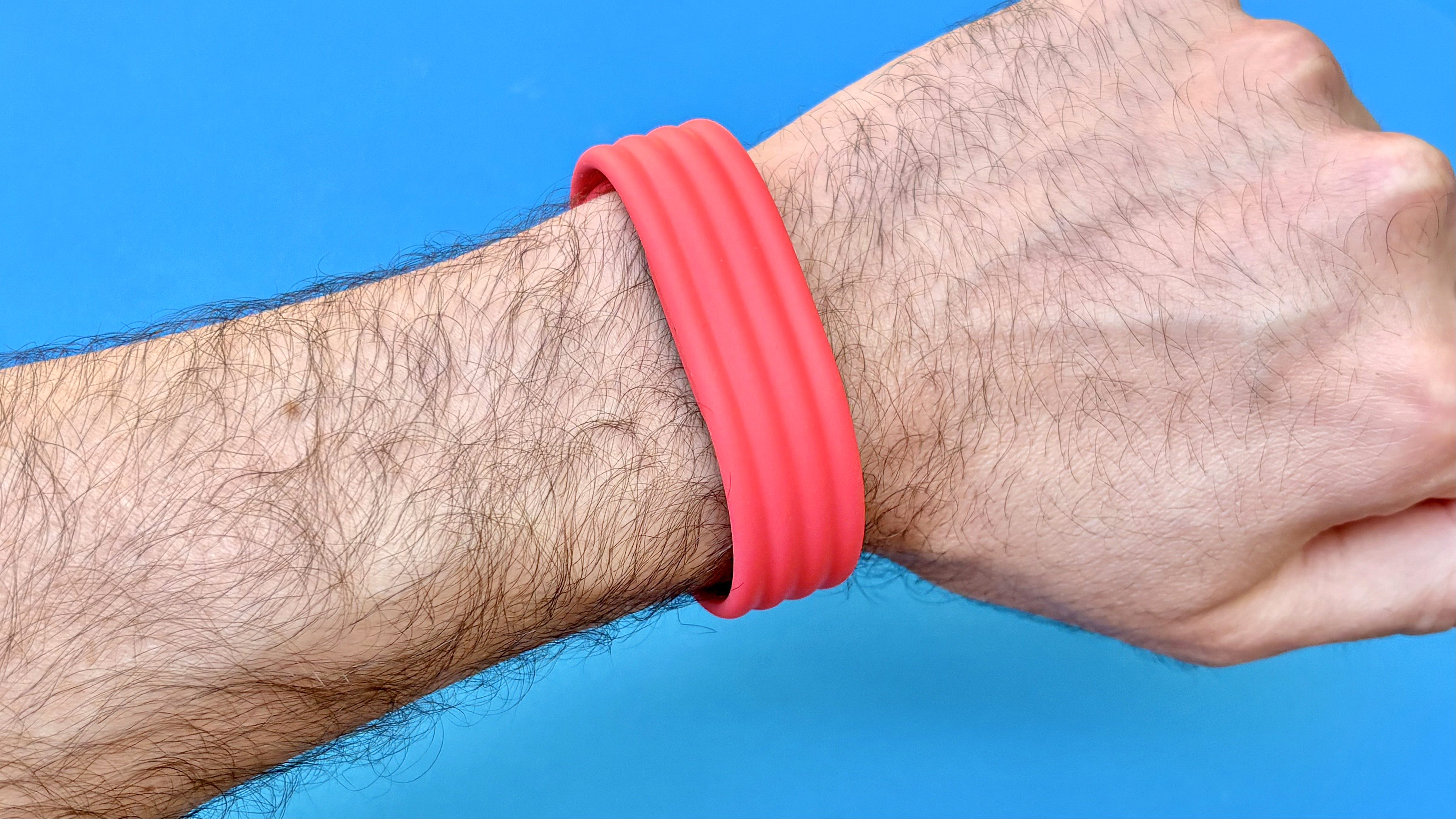 Close-up of the Fitbit Air on-wrist on a red strap against a blue background