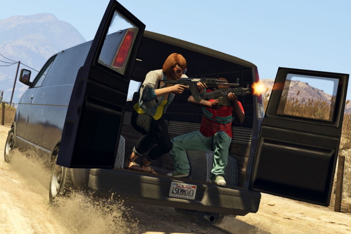 Two characters in a van shooting guns in GTA Online, with open doors and a dusty landscape in the background.