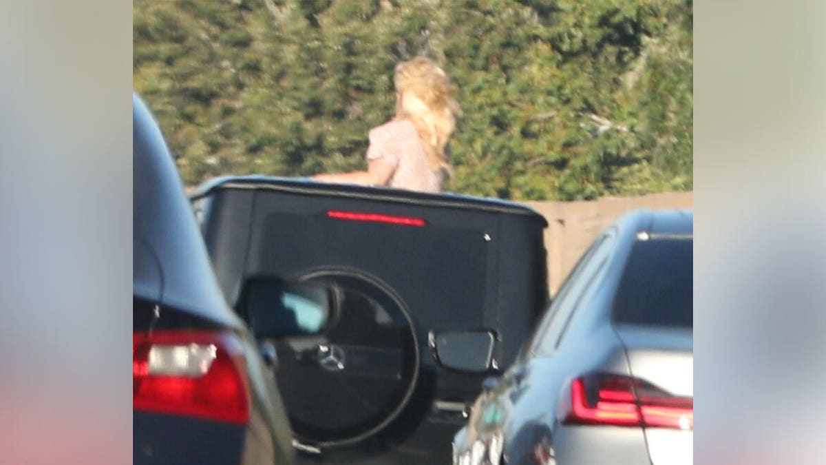 Britney Spears standing out of the sunroof of her Mercedes SUV.