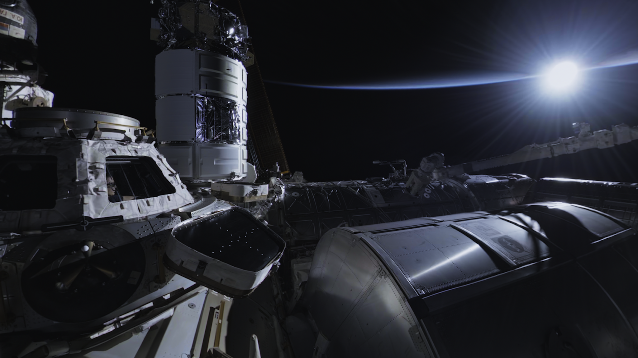 A photo of the exterior of the ISS with the sun shining in the background.
