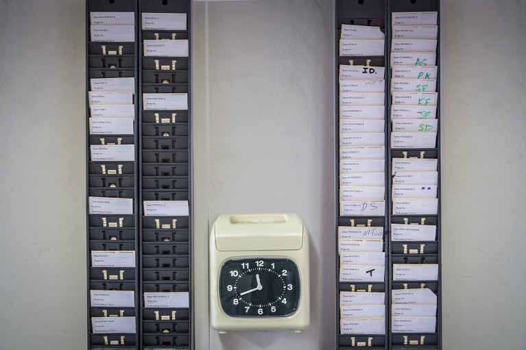 A wall mounted time recording card machine for employees to clock in with time cards.