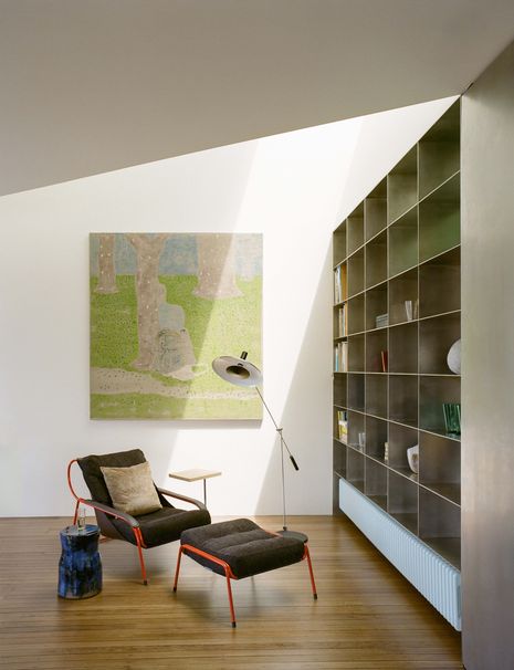 The ceiling was re-engineered with a deep, vaulted skylight positioned above a floor-to-ceiling bookcase, which structurally divides the living area from the bathroom.