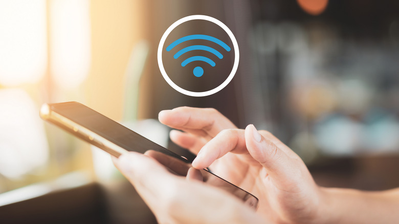 A person using a phone with a Wi-Fi logo in the background.