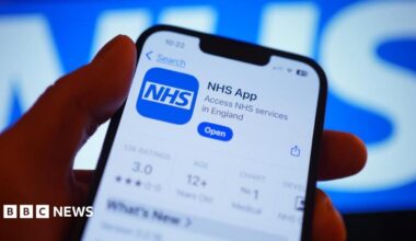 A hand holds a smartphone displaying the NHS app after it has been downloaded.