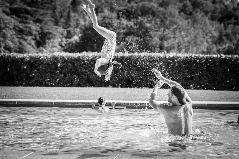 Prince Harry can be seen donning a backwards cap while throwing his daughter in the pool.