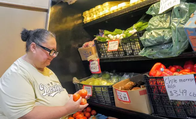 Ada Torres holds tomatoes while shopping for produce, Thursday, July 2, 2026, in Cleveland, Texas, about 45 miles northeast of Houston. (Sandy Guatibonza/La Esquina TX via AP)