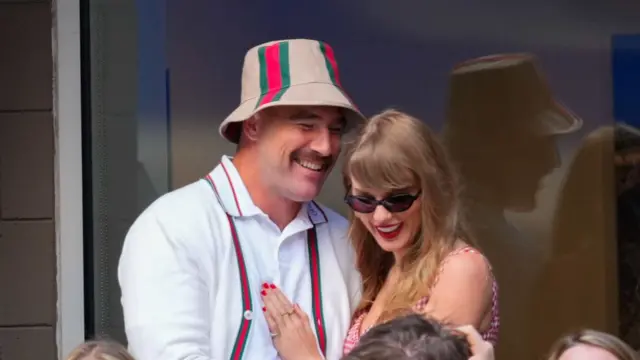 Travis Kelce and Taylor Swift stand in the stands at a tennis match in New York