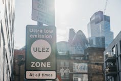 ULEZ green road sign, london buildings in background.