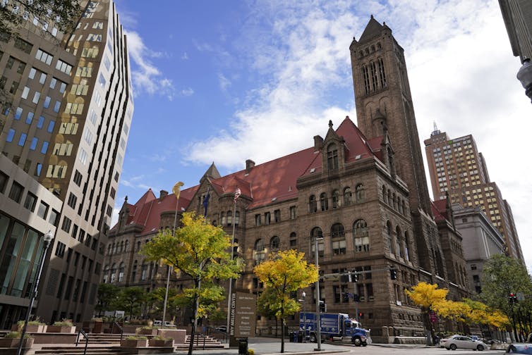 A large, old stone building in the middle of a city.