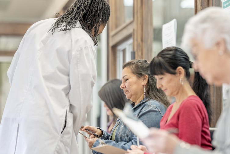 A healthcare worker speaks to a patient in a clinic waiting room