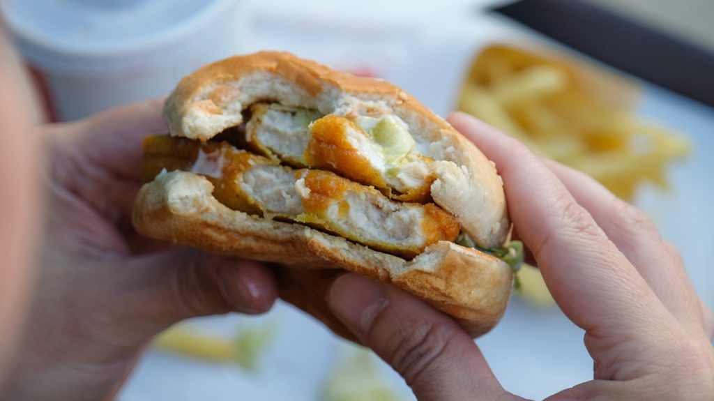hands holding chicken nugget burger patty