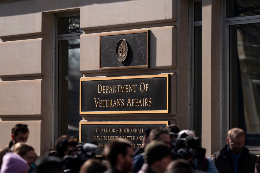 Members of the media stand near a rally happening outside the Department of Veterans Affairs headquarters in Washington, DC, on February 13, 2025.