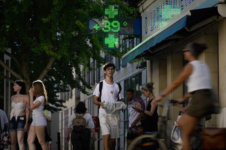 Pedestrians pass a pharmacy sign reading 39 degrees Celsius in Bordeaux, southwestern France, on Monday. Three-quarters of the country was under a heatwave alert on Tuesday.
