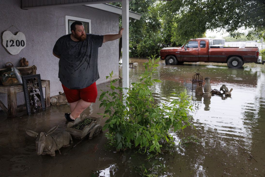 Skylor Dozier stands on the front porch of a flooded house along North Camp Street in Uvalde, Texas on Thursday, July 16.