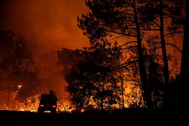 A firefighter sprays water from a truck close to a residential area during a wildfire near Lège-Cap-Ferret.