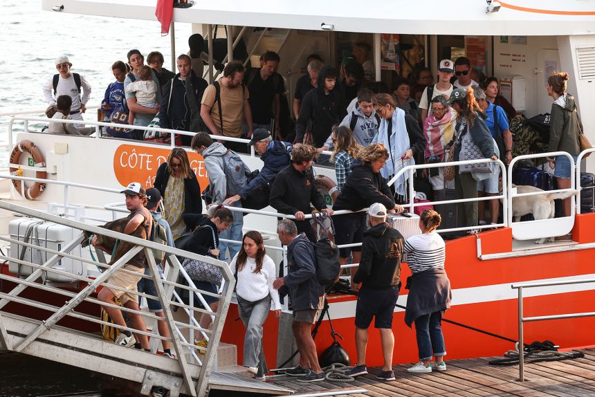 Holidaymakers from Lège-Cap-Ferret disembark from a boat in Arcachon during an evacuation operation of the entire Cap-Ferret peninsula, in southwestern France, on Friday, as a wildfire spreads across the area.