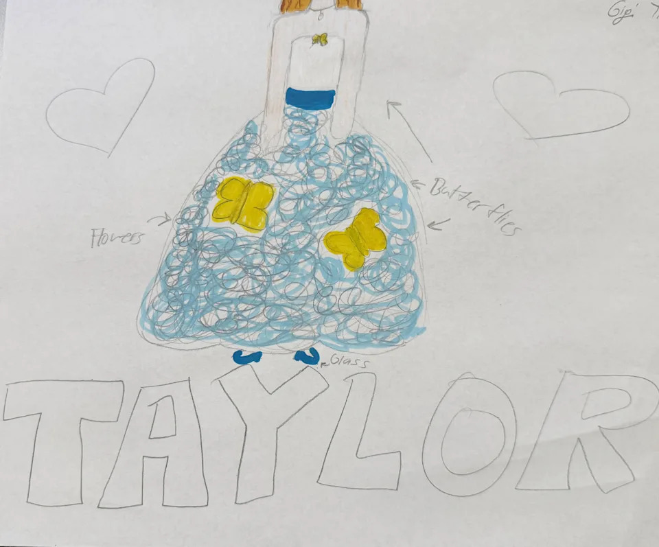 A child's colored drawing of a wedding dress with a white bodice and a full light-blue skirt covered in swirling designs. Large yellow butterflies decorate the skirt, with handwritten labels pointing out the butterflies, flowers and glass slippers.