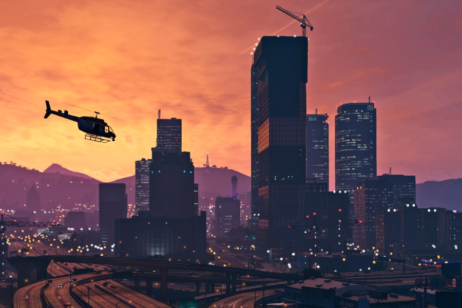 Helicopter flying over Los Santos cityscape at sunset in Grand Theft Auto V.