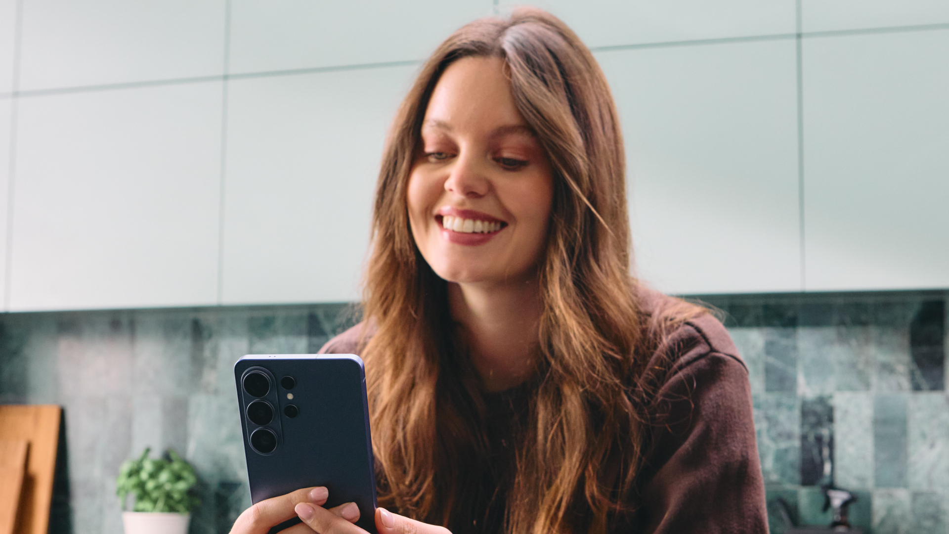 A woman using a Samsung Galaxy S26 Ultra, smiling.