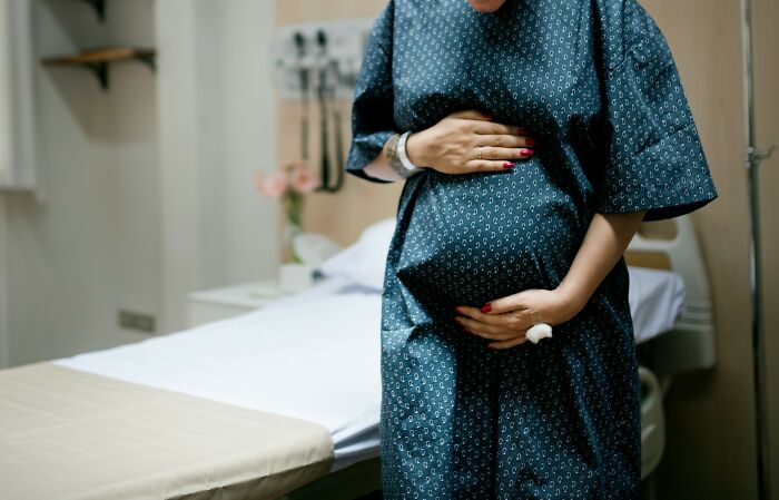 A pregnant woman in a hospital gown, embodying hospital employees' experiences with horror stories.
