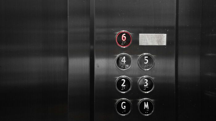 A hand pressing an elevator button, symbolizing a hospital employee's horror stories in a medical facility.