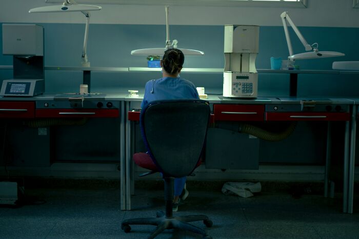A hospital employee works alone at a desk in a dimly lit lab, evoking eerie hospital horror stories.