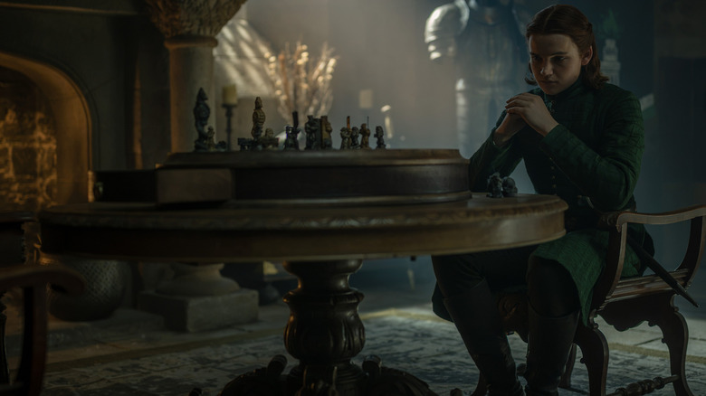 Benjamin Evan Ainsworth as Daeron Targaryen sitting at a table with toy figures on it in House of the Dragon