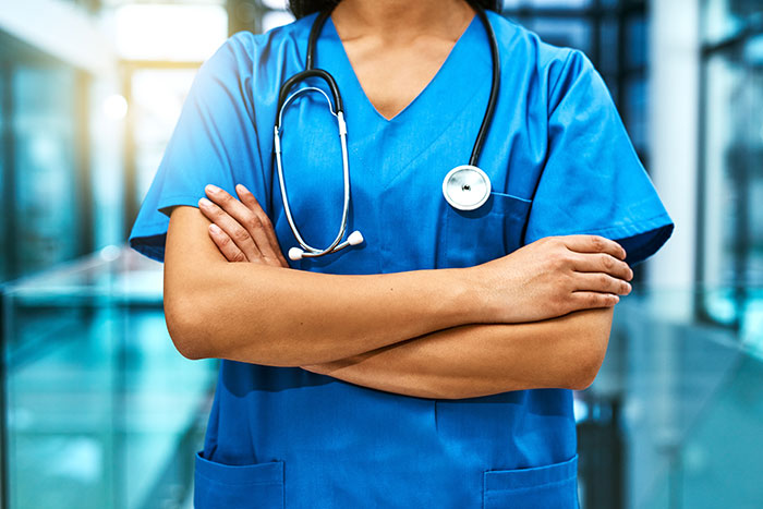 A doctor in blue scrubs with a stethoscope, arms crossed, representing medical symptoms.