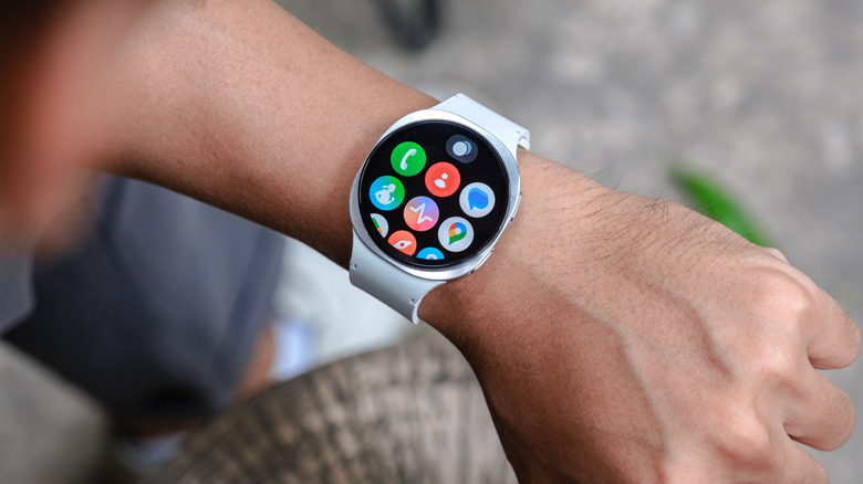 A Samsung Galaxy Watch with a white band adorns a user's right wrist