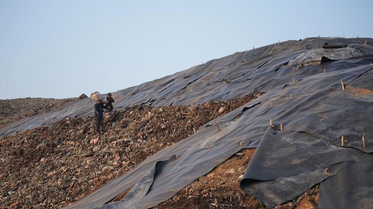 Waste pickers walk near a tarped section at the Bantargebang landfill.