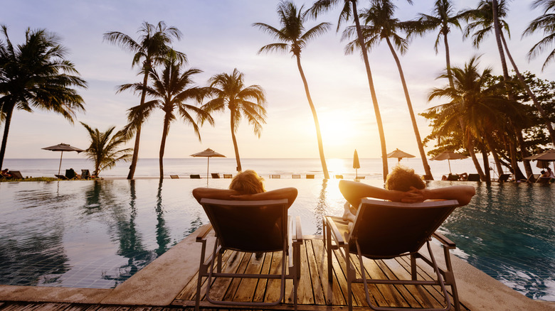 A couple lounging beside a swimming pool in the summer.