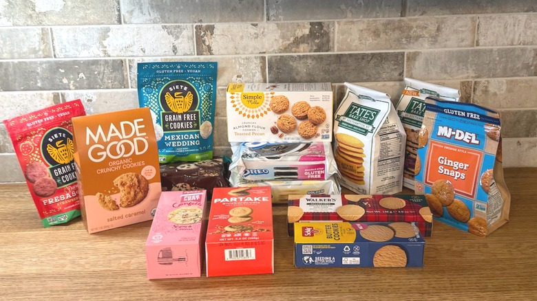 Multiple brands of store-bought gluten-free cookies on table against a brick backsplash