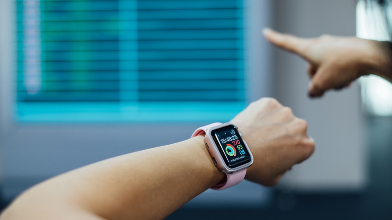 A person looking at the schedule of flights in an airport, with an Apple Watch on their wrist.