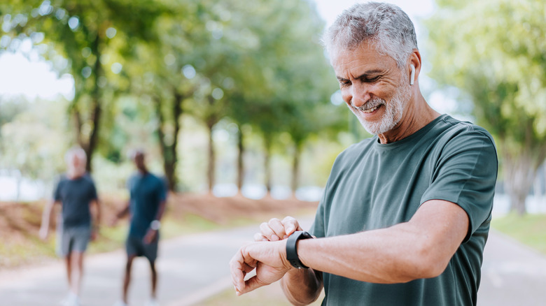 Senior man runner looking at smartwatch outdoor activity