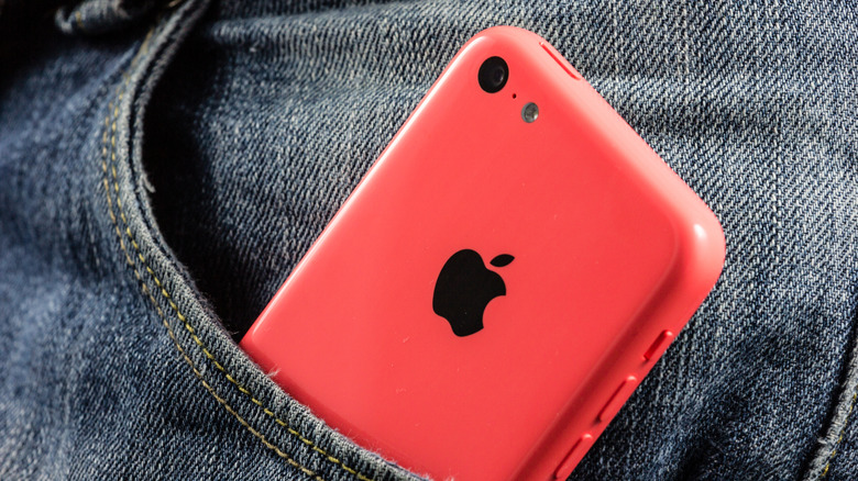 The bright red iPhone 5c in a person's jeans pocket