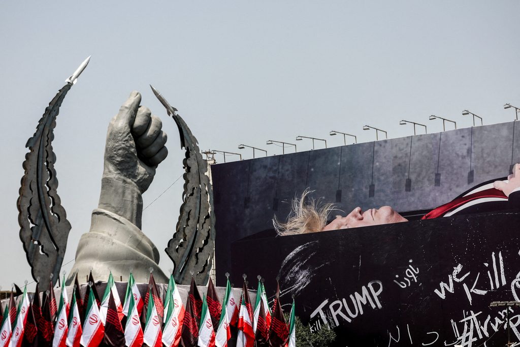 A statue symbolising the hand of Iran's late Supreme Leader Ayatollah Ali Khamenei next to a billboard depicting U.S. President Donald Trump laid in a coffin, in Tehran
