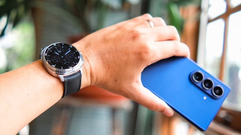 A person wearing a Galaxy Watch8 on his wrist while holding the Galaxy Fold7