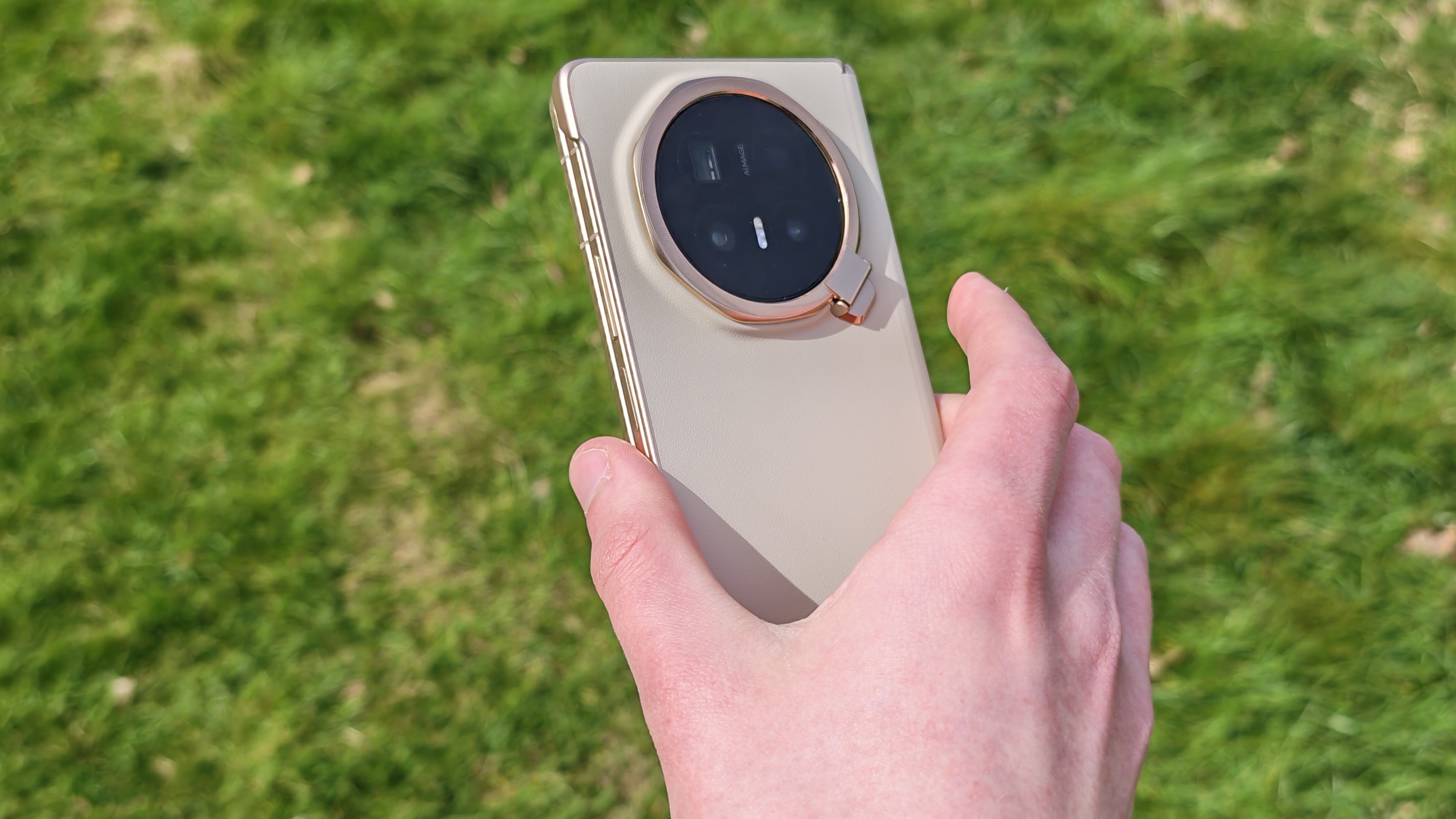 The Honor Magic V6 being held in a sunny field.