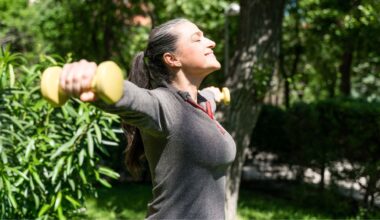 Woman doing lateral raise exercise in garden sunshine