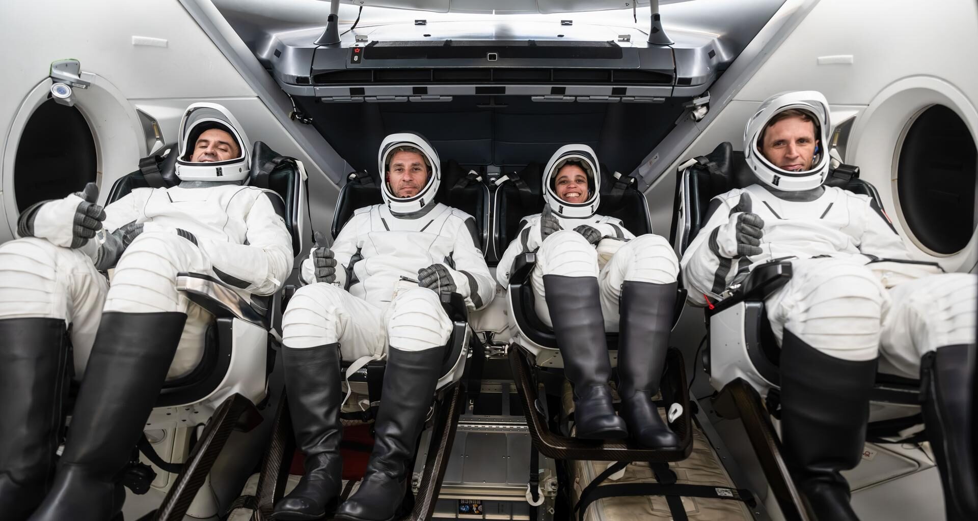 The SpaceX Crew-13 members are pictured in their pressure suits seated inside a mockup Dragon spacecraft during a preflight training session at the company's headquarters in Hawthorne, California. From left are, Roscosmos Sergey Teteryatnikov, NASA astronauts Luke Delaney and Jessica Watkins, and CSA (Canadian Space Agency) astronaut Joshua Kutryk.