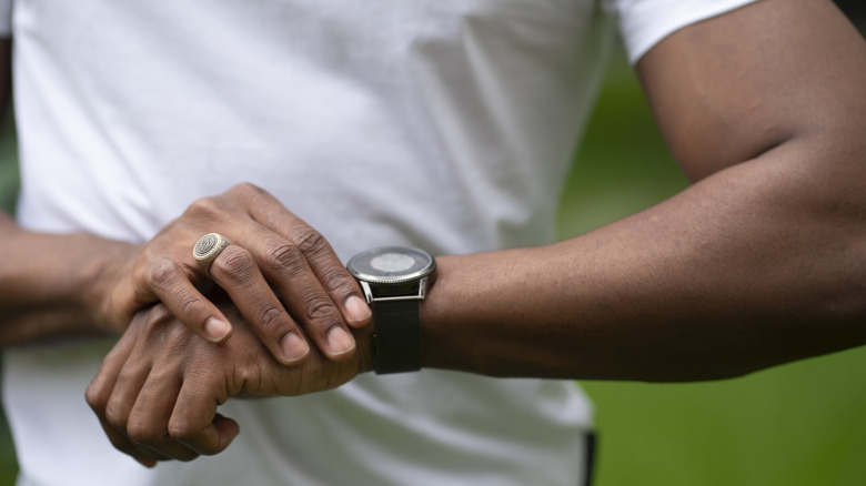 A man outside looking at his smartwatch.