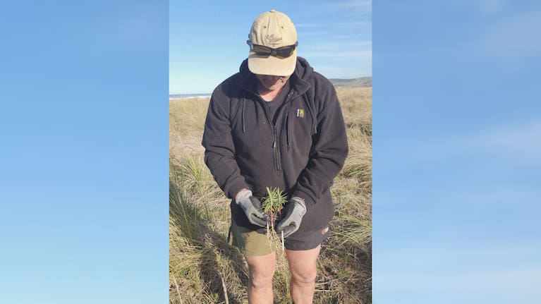 Luke Shadbolt holds the invasive and potentially dangerous pest plant caper spurge.