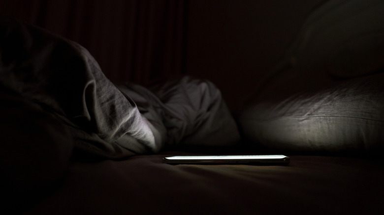 A phone placed on a bed in a dark room