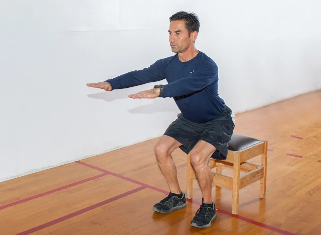 Middle age man demonstrates bench squat strength exercise.