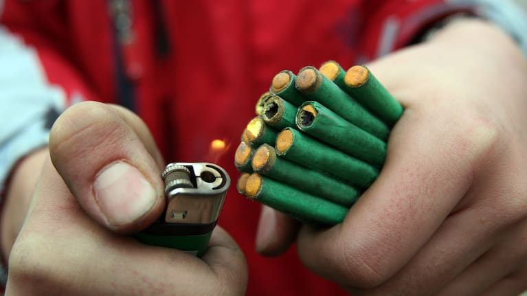 Man holding a handful of fireworks, stock image.