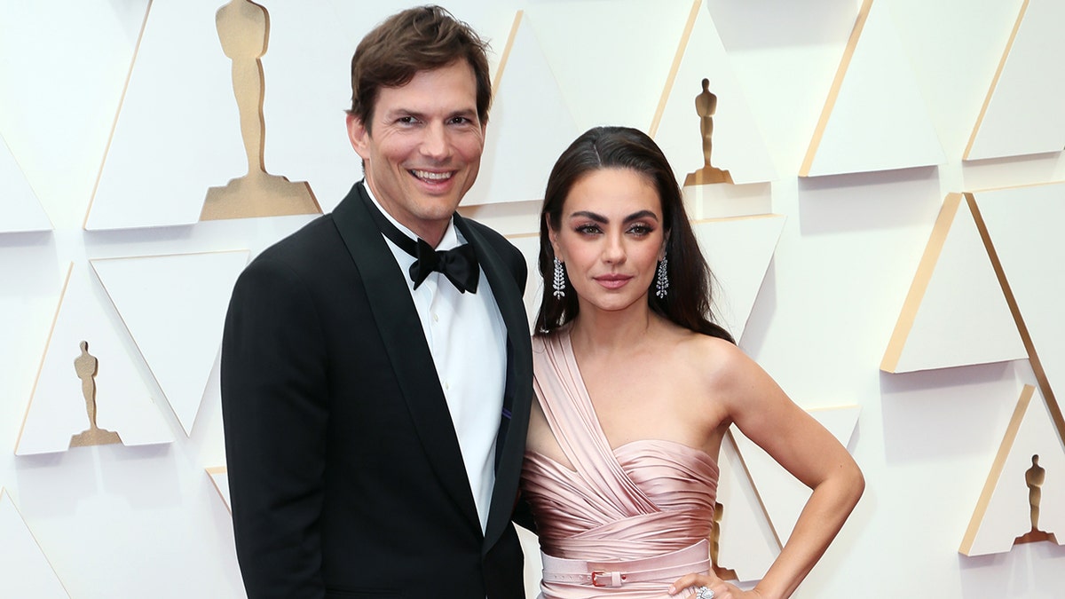 Mila Kunis and Ashton Kutcher standing together outdoors.