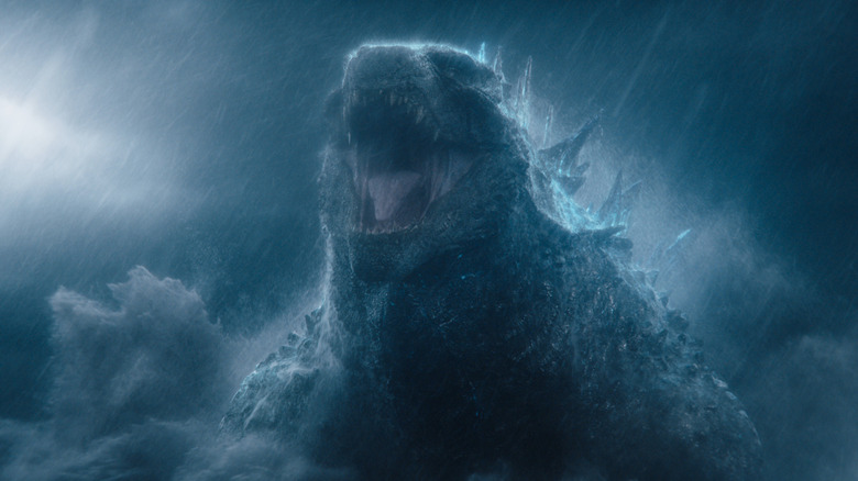 Godzilla, a monstrously large lizard with huge dorsal fins, roars in the middle of a storm as waves crash around him.
