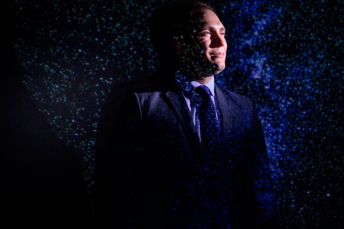 Jonathan Blazek, assistant professor of physics at Northeastern University, portrait against a starfield backdrop.